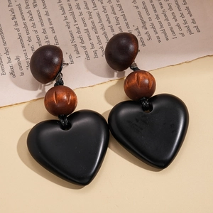 Detail of vintage acrylic drop earrings featuring brown wooden beads and black heart pendant