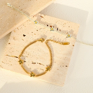 Star charm bracelets in gold and silver steel with yellow zircon stones on stone background
