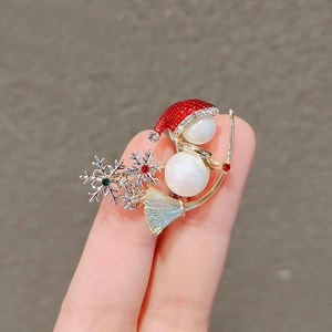 Close-up of a Christmas snowman brooch with red enamel hat, pearls, and sparkling crystals