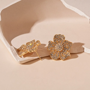 Detailed macro view of gold-plated flower stud earrings with sparkling pavé crystals
