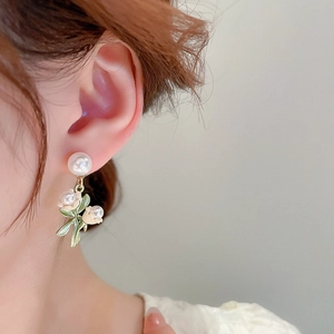 Détail des boucles d'oreilles perles muguet portées par un mannequin en gros plan