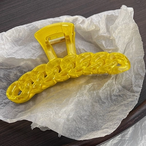 Close-up of a large yellow candy-colored chain design hair claw clip on a white background