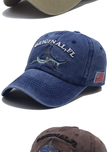 Detail of embroidered shark and US flag patches on washed cotton baseball caps in varied colors