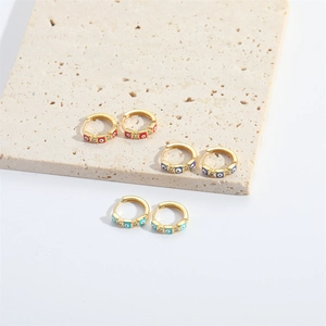 Golden huggie hoop earrings featuring colorful enamel evil eyes and sparkling zircon accents