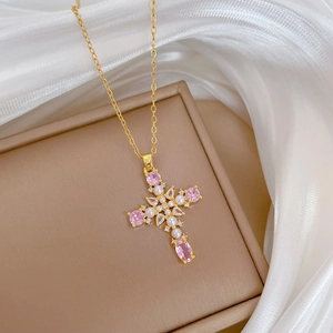 Detail of cross pendant with pink gemstones and white pearls on luxurious silk