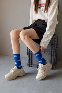 Detail of blue knit socks with white cloud patterns paired with beige chunky sneakers
