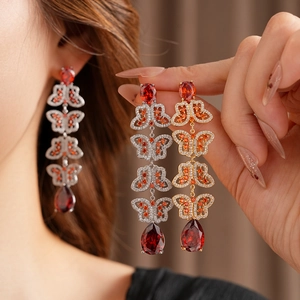 Gros plan de boucles d'oreilles papillon à pampilles avec pierres rubis et placage argent