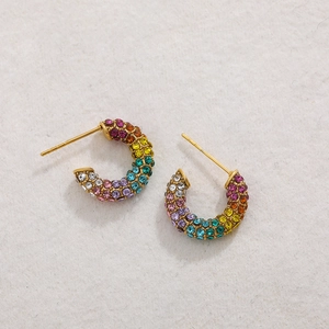 Detailed macro view of gold-plated C-shaped earrings with rainbow pave crystal settings