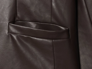 Détail de la poche latérale d'une veste en cuir marron foncé avec coutures et texture