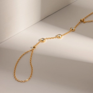 Detailed close-up of golden stainless steel chain with white zircon stones on a pedestal