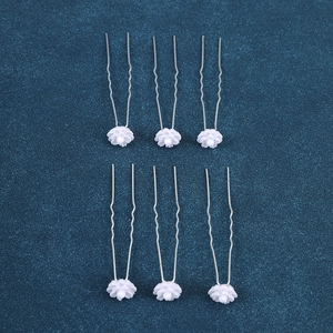Detail of bridal U-shaped hair pins with white floral decorations and silver metal wave pins