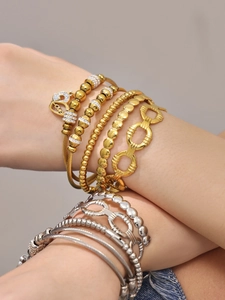 Détail de bracelets superposés en or et argent avec zircons 5A et breloques Love