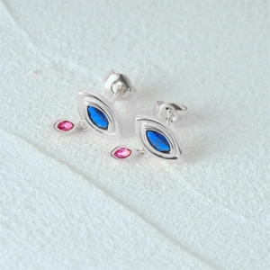 Macro view of silver eye-shaped earrings with marquise blue and teardrop pink stones