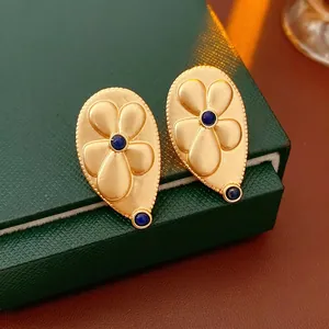 Vintage gold teardrop earrings with embossed floral design and blue gemstones