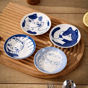 Japanese ceramic cat sauce dishes set on a textured wooden tray for dining