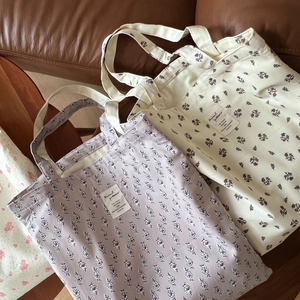 Detailed close-up of floral print cotton tote bags on a brown leather surface