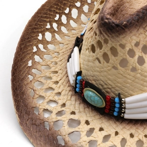 Detail of straw cowboy hat with turquoise ethnic beaded band and open-weave texture