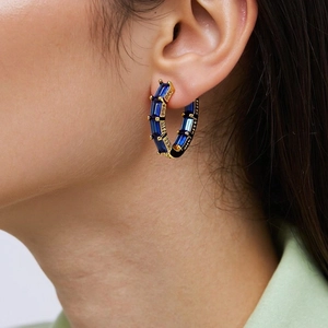 Macro shot of gold hoop earring featuring rectangle cut navy blue zircon stones