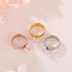 Trois bagues en zircone carrée en or, or rose et argent sur fond rose pastel