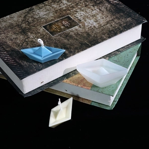 Detailaufnahme von handgefertigten Kerzen in Papierboot-Optik auf antiken Büchern