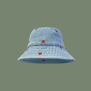Light blue denim bucket hat with red heart embroidery on a soft green background