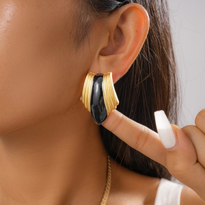 Close-up of vintage black and gold enamel earrings with a wavy metal texture finish