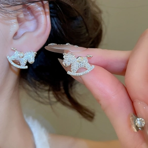 Close-up of silver rocking horse stud earrings with sparkling pave-set diamonds