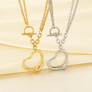 Détail de colliers cœur en or et argent avec fermoir à bascule sur tissu en soie