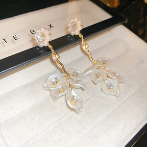 Close-up of golden pearl earrings with cascading white flower petals and zircon details