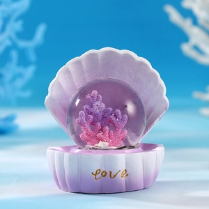 Luminous crystal ball with pink coral inside a shell-shaped love base for ocean decor