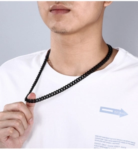 Close-up of a men's chunky black stainless steel Cuban link chain necklace on a model