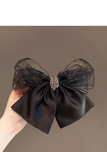 Detail of a large black mesh bow hair clip with sparkling rhinestones held in hand
