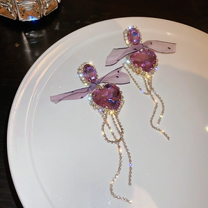 Detail of purple heart gemstone earrings with silk bow and sparkling rhinestone tassels