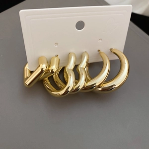 Ensemble de boucles d'oreilles dorées avec créoles épaisses et cœurs sur carte présentoir