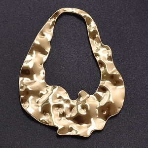Macro shot of gold 304 stainless steel pendant with hammered texture and irregular hollow shape