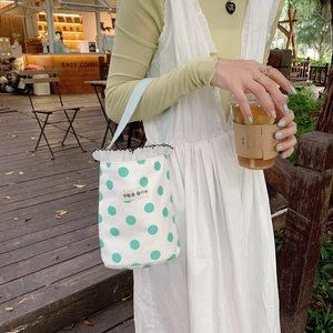 Detailed view of white canvas mini lunch bag with green polka dots and ruffle trim