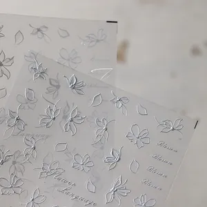 Detailed macro of 5D silver embossed floral nail stickers with butterfly patterns