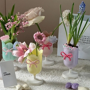 Close-up of pastel macaron-colored tulip vases with 3D bow details on white pedestal stands