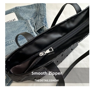 Detailansicht eines silbernen Reißverschlusses an einer schwarzen Leder-Shopper-Tasche