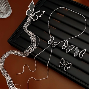 Detailed set of silver butterfly hair clips, necklaces, and rings on black display tray