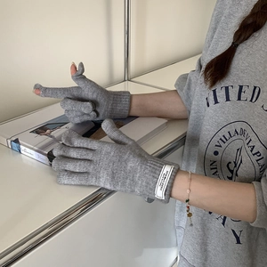 Detail of grey knitted flip-top touchscreen gloves with white label and soft texture