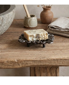Detail of vintage cast iron soap dish with bronze hollow floral pattern and artisan soap