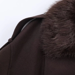 Détail du col en fausse fourrure marron foncé et du tissu texturé sur l'épaule de la veste