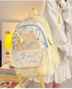 Detail view of a beige high-capacity school backpack with decorative embroidery and side pockets