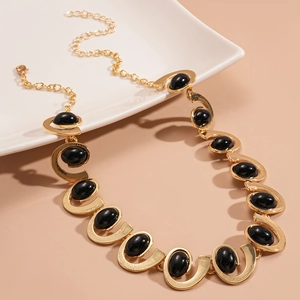 Vintage gold chunky chain necklace with black oval resin stones on beige background