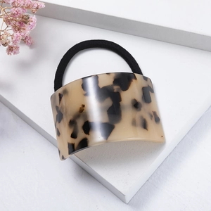 Close-up of tortoise shell pattern acetate geometric hair tie on a white pedestal