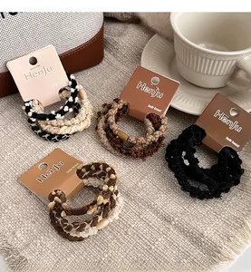 Close-up of four high-elasticity braided hair ties in coffee tones on a textured tablecloth