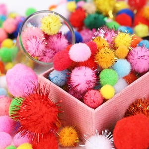 Macro shot of colorful craft pom-poms with tinsel details in a pink storage box