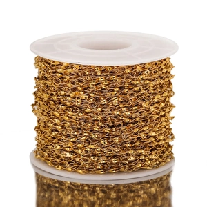 Macro detail of 18K gold-plated stainless steel twisted Cuban chain on a white spool