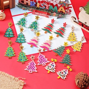 Detailed view of rhinestone Christmas tree earrings with colorful beads on festive red backdrop